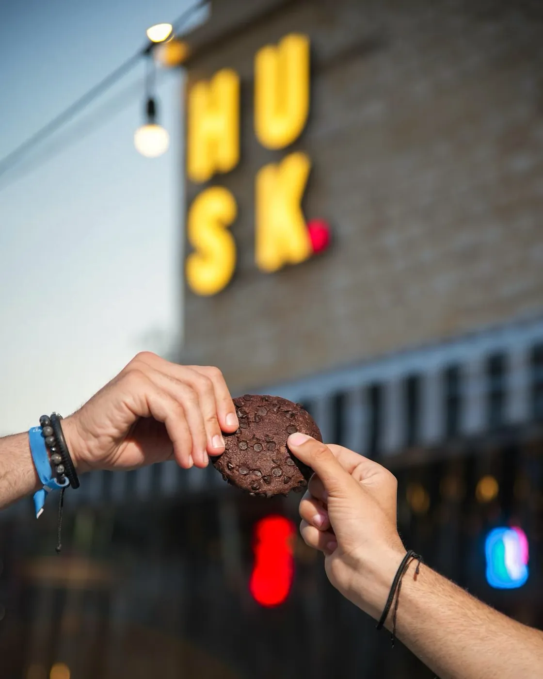 Handing over a cookie outside Husk at night